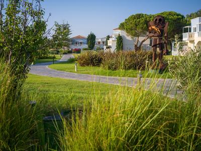 Grünes Rasengelände mit gepflastertem Weg und modernen Gebäuden im Hintergrund unter klarem Himmel