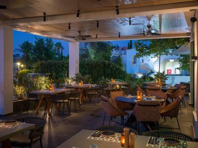 Elegantní restaurace na terase večer, dřevěné stoly a pohodlné židle pod otevřenou střechou.