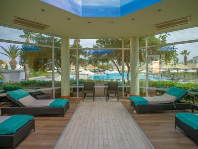 Pohodlná odpočinková zóna s pohovkami a výhledem na bazén obklopený palmami.