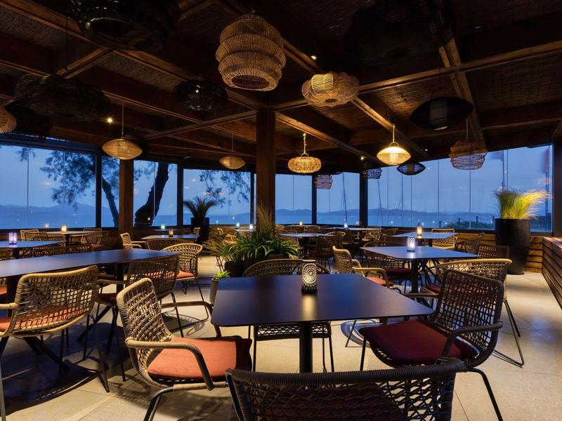 Otevřená restaurace terasa s pohodlnými stoly a židlemi při soumraku.