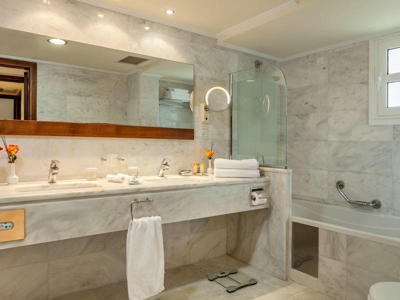 Moderní koupelna s velkým zrcadlem, dvojnásobným umyvadlem a vanou pod oknem.