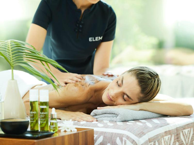 Žena dostává relaxační masáž ve wellness se zimními oleji a zen dekoracemi.