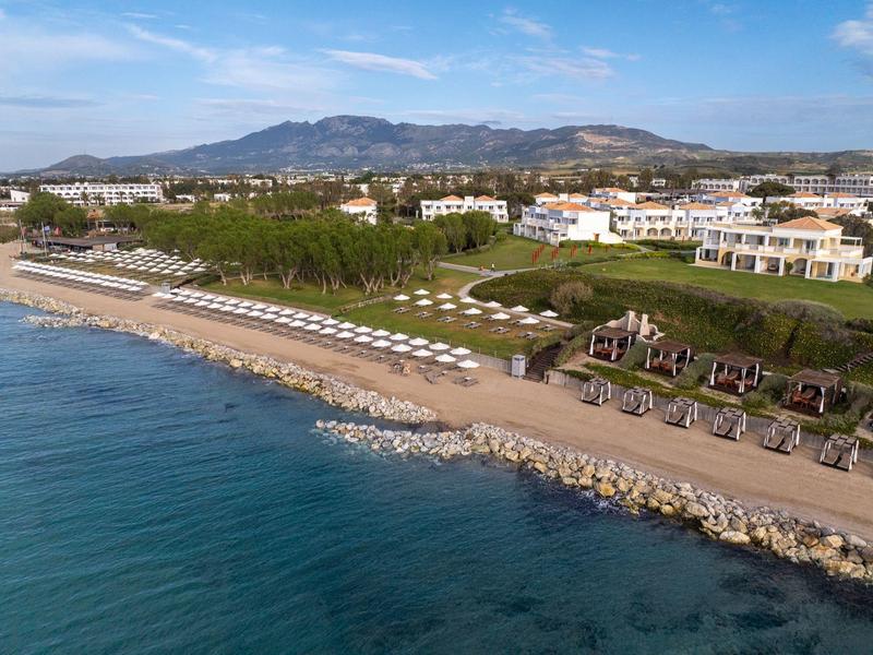 Klidná pláž s lehátky, altány a výhledem na hory za hotelem.