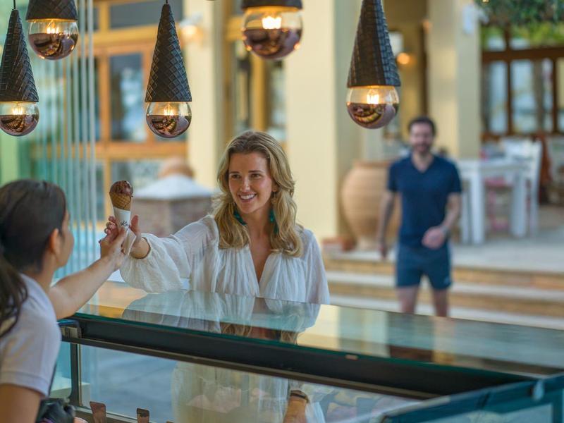 Dvě ženy si užívají zmrzlinu před výlohou rušné ulice.