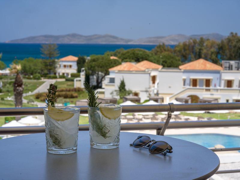 Dvě sklenice s osvěžujícím nápojem na stole u bazénu s výhledem na moře.