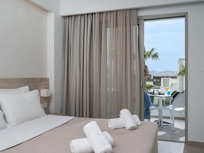 Modernes Hotelzimmer mit Doppelbett, weißen Handtüchern und Zugang zu Balkon mit Meerblick.