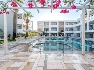 Area piscina esterna moderna di un hotel con posti a sedere e piante in fiore.