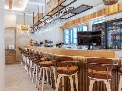 Area bar moderna dell'hotel con sgabelli in legno e illuminazione calda.