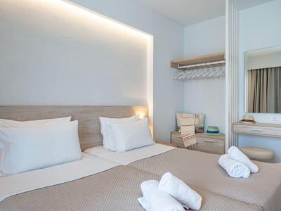 Helles Hotelzimmer mit zwei Einzelbetten, jeweils mit weißen Kissen und Handtüchern.