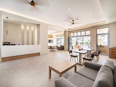 Moderner Hotel-Lobby-Bereich mit Sofa, Tisch und Sitzgelegenheiten neben großen Fenstern.