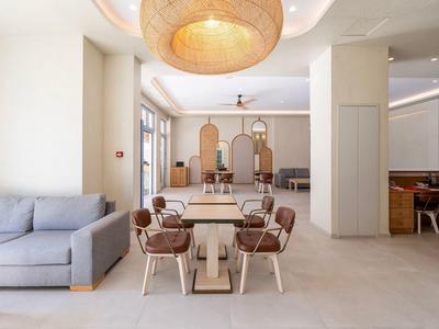 Heller, moderner Essbereich mit Holztischen, Stühlen und einem großen runden Deckenlicht.