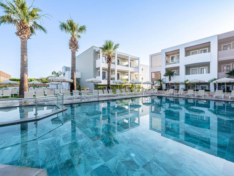 Moderner Hotelpool mit Palmen und Liegestühlen unter klarem Himmel.