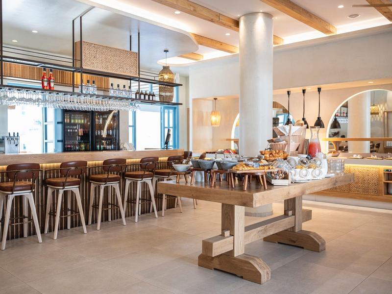 Modern eingerichteter Frühstücksraum mit Bartresen und Buffetplatte in warmen Holztönen.