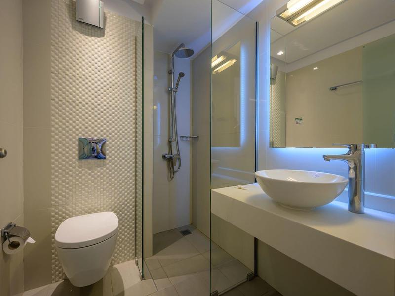 Modernes Badezimmer mit weißer Toilette, Glasdusche und Waschbecken auf breitem Waschtisch.