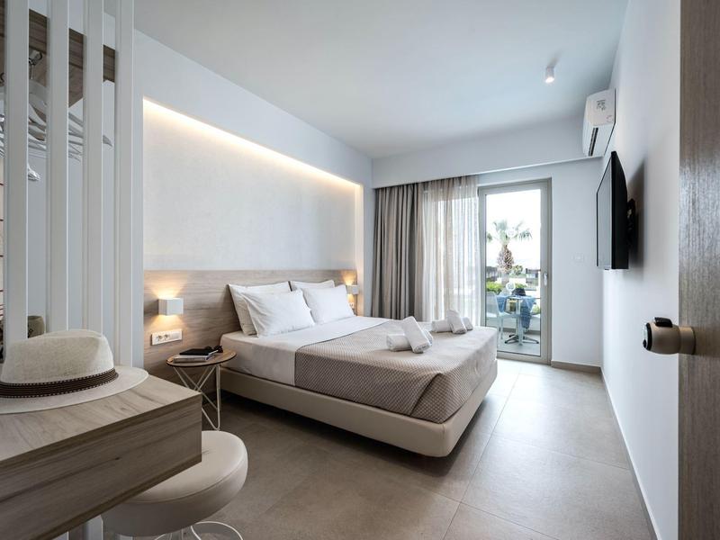 Modernes Hotelzimmer mit Doppelbett, Schreibtisch, Balkon und neutralen Farben.