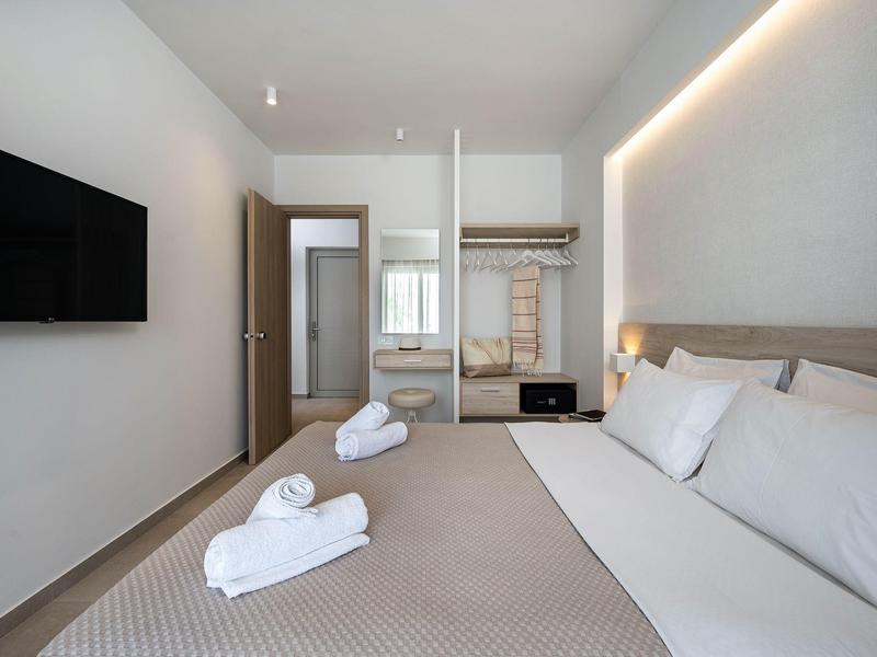 Modernes Hotelzimmer mit großem Bett, Fernseher und offenem Kleiderschrank.