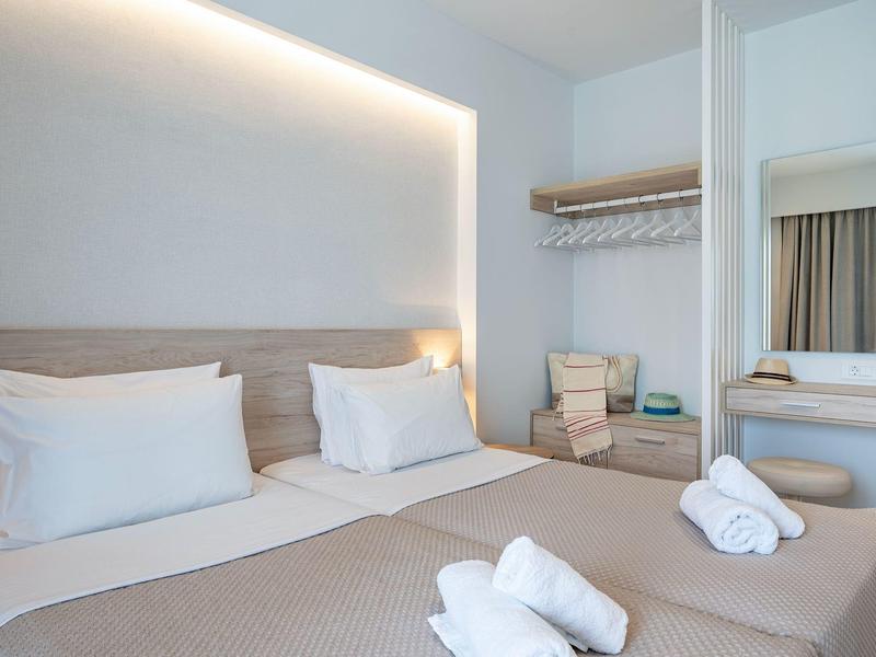 Helles Hotelzimmer mit zwei Einzelbetten, jeweils mit weißen Kissen und Handtüchern.