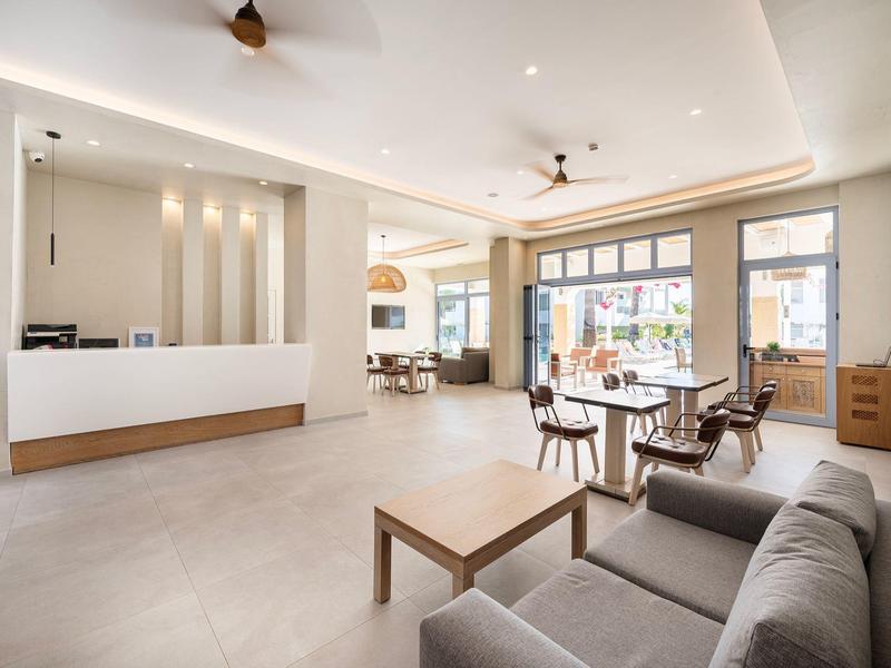 Moderner Hotel-Lobby-Bereich mit Sofa, Tisch und Sitzgelegenheiten neben großen Fenstern.