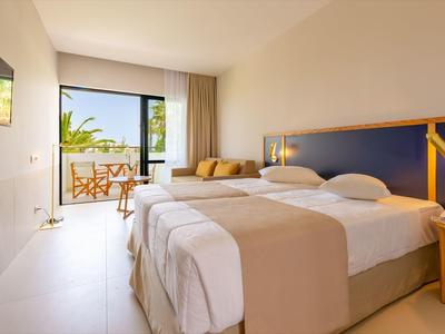 Modern hotel room with double bed, balcony, and sea view.