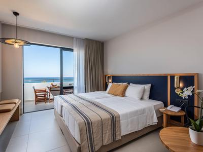 Modernes Hotelzimmer mit Doppelbett, Balkon und Blick auf das Meer.
