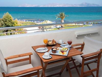 Balcony with breakfast table overlooking the blue sea and beach.