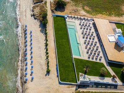 Aerial view of a hotel with pool, sun loungers, and direct access to the beach.