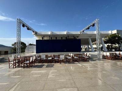 Freiluftkino mit Stuhlreihen und großen Lautsprechertürmen bei Tageslicht.