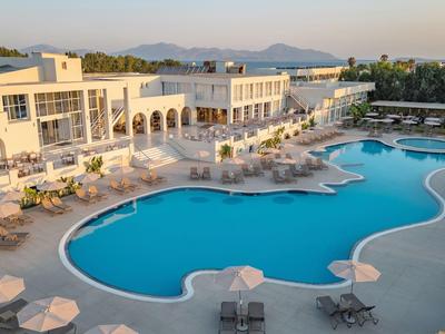 Großer Hotelpool mit Liegestühlen und Sonnenschirmen in einem Resort bei Sonnenuntergang.