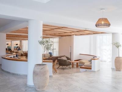 Bright hotel lobby area with white walls, seating, and large ceramic vases.