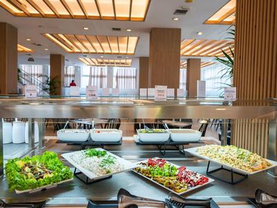 Buffet with fresh salads in a modern dining area with large windows.