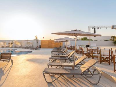 Poolbereich mit Liegestühlen und Sonnenschirmen bei Sonnenuntergang.