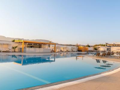 Large outdoor pool with lounge chairs and clear sky at sunset.