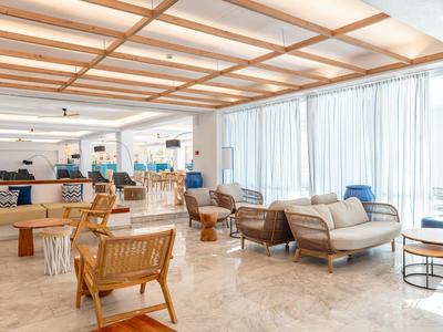 Bright hotel lounge area with comfortable chairs, sofas, and large windows.