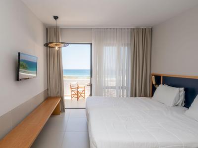 Modernes Hotelzimmer mit Doppelbett, TV und Balkon mit Meerblick.