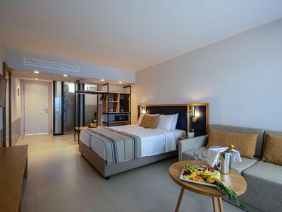 Modernes Hotelzimmer mit Doppelbett, Couch und einem Tisch mit Frühstück.