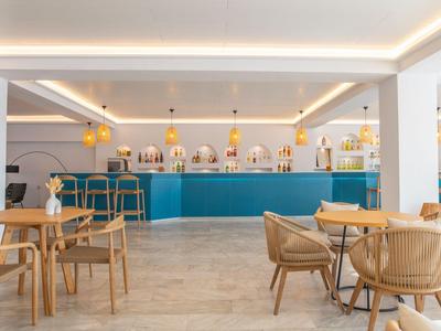 Moderner Hotelbarbereich mit blauer Theke, runden Holzstühlen und heller Beleuchtung.