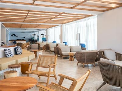 Heller Hotel-Loungebereich mit modernen Holzmöbeln und großen Fenstern.