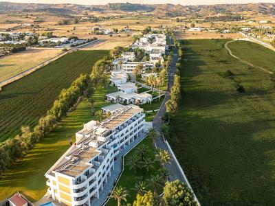 Luftaufnahme eines Hotels neben einem grünen Feld und einem offenen Landschaftshintergrund.