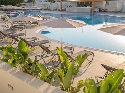Moderner Poolbereich mit Sonnenliegen, Sonnenschirmen und grünen Pflanzen in einem Hotel.