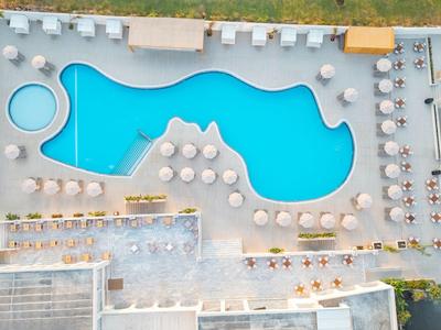 Vogelperspektive eines modernen Hotelpools mit Liegestühlen und Sonnenschirmen.