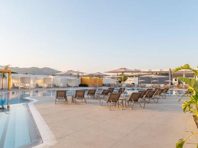 Moderner Hotelpool mit Liegestühlen und Sonnenschirmen bei klarem Himmel.