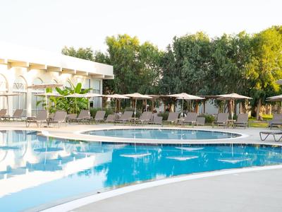 Moderner Hotelpool mit Liegestühlen und Sonnenschirmen in einer grünen Umgebung.