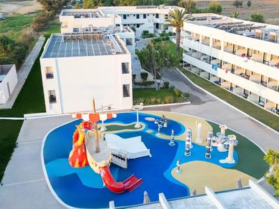Moderner Spielplatz mit bunten Rutschen neben mehrstöckigen Hotelgebäuden in ländlicher Umgebung.