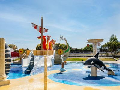 Freizeitpark mit Wasserattraktionen wie Delfinen, einer Drachenskulptur und einem Pools im sonnigen Tag.