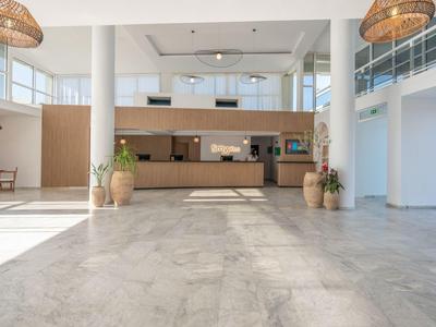 Helle Hotellobby mit großer Rezeption, moderner Einrichtung und Pflanzen