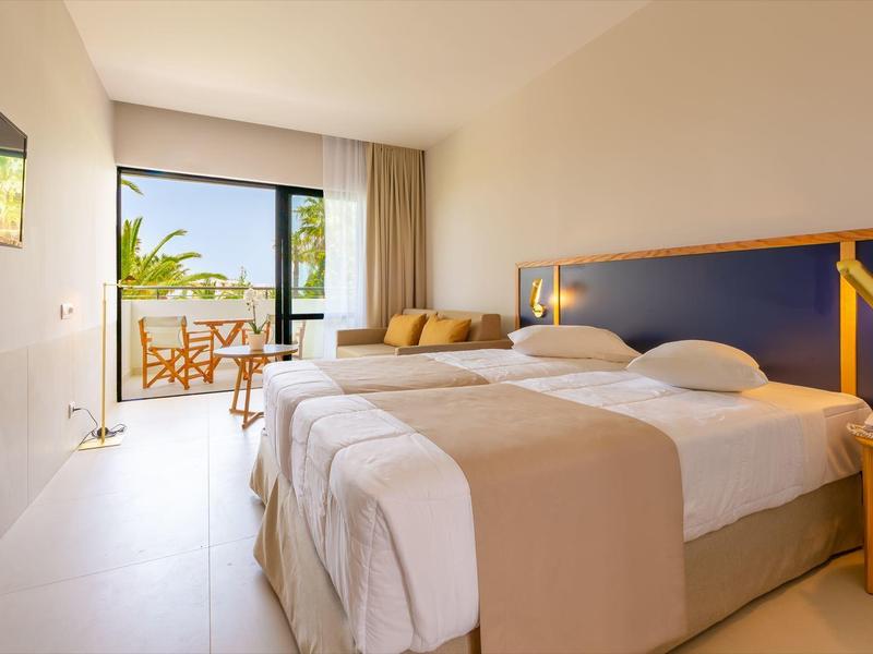 Modern hotel room with double bed, balcony, and sea view.