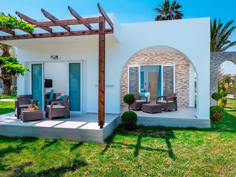 Modern guesthouse with terrace, seating areas, and a beautiful garden in sunny weather.