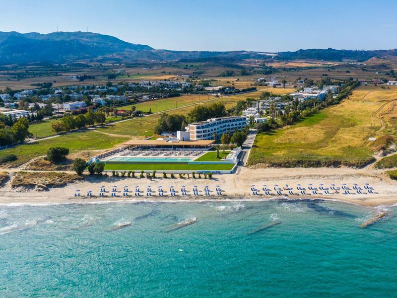 Aerial view of a beach resort with a pool and mountains in the background.