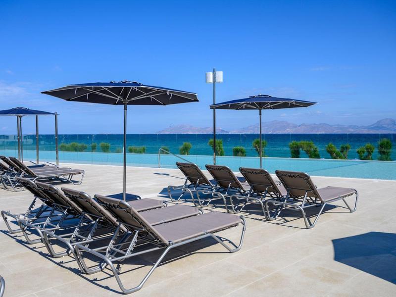 Sun terrace with loungers and umbrellas by the pool overlooking the sea.