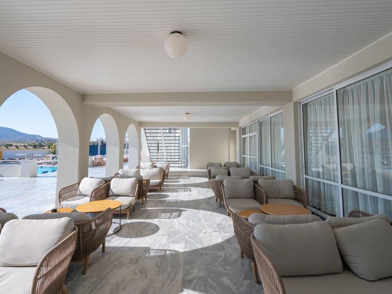 Covered terrace with comfortable armchairs, tables, and a view of the pool.